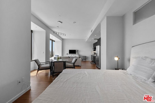 bedroom with dark hardwood / wood-style floors and stainless steel fridge with ice dispenser