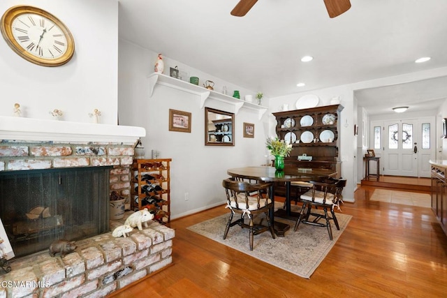 dining space with ceiling fan, a fireplace, and hardwood / wood-style floors