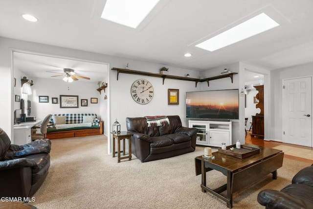 living room featuring light carpet, ceiling fan, and a skylight