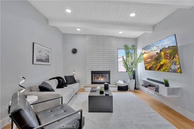 living room with beamed ceiling, a fireplace, light hardwood / wood-style floors, and wooden ceiling