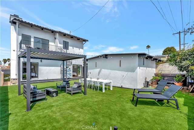 back of property featuring outdoor lounge area, a balcony, a yard, and a hot tub