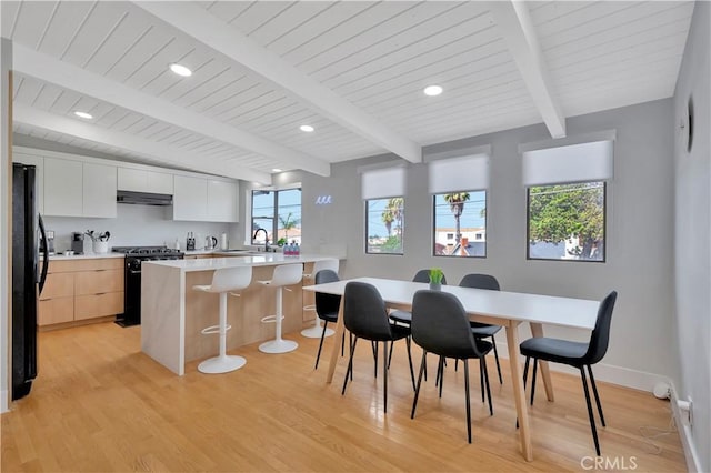 kitchen featuring a kitchen bar, black appliances, a center island, light hardwood / wood-style flooring, and white cabinets