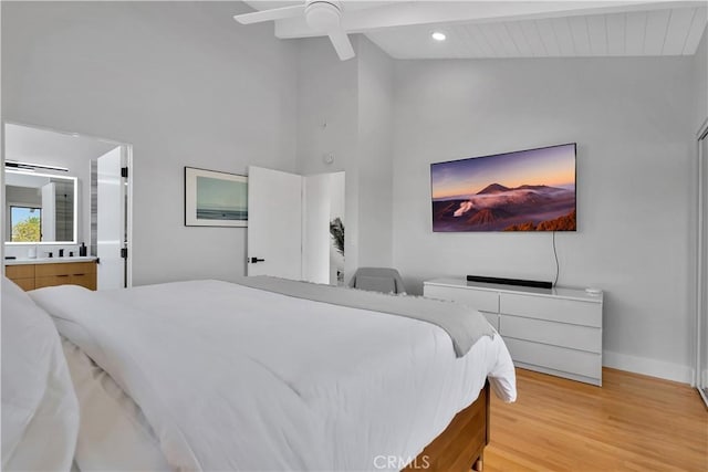 bedroom featuring ensuite bathroom, high vaulted ceiling, hardwood / wood-style flooring, ceiling fan, and beam ceiling