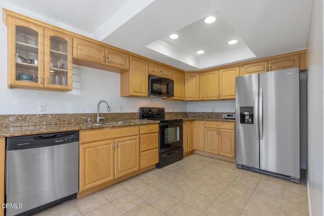 kitchen with sink, crown molding, dark stone countertops, a tray ceiling, and black appliances