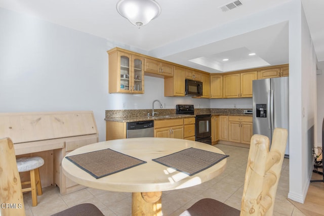 kitchen with light tile patterned flooring, light brown cabinetry, sink, black appliances, and a raised ceiling