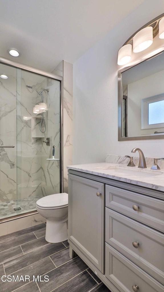 bathroom featuring vanity, toilet, and walk in shower