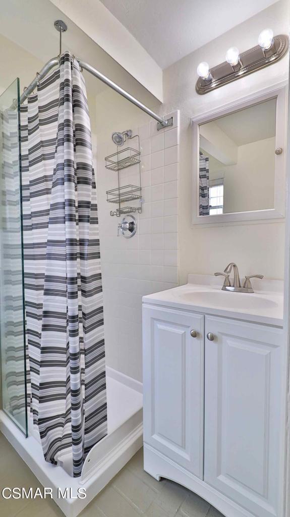 bathroom with a tile shower, vanity, and tile patterned flooring