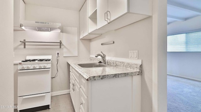 kitchen featuring white gas range, sink, light carpet, and white cabinets