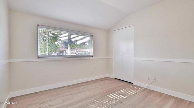 spare room with lofted ceiling and light hardwood / wood-style floors