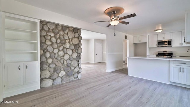 kitchen featuring built in features, ceiling fan, appliances with stainless steel finishes, white cabinets, and light wood-type flooring