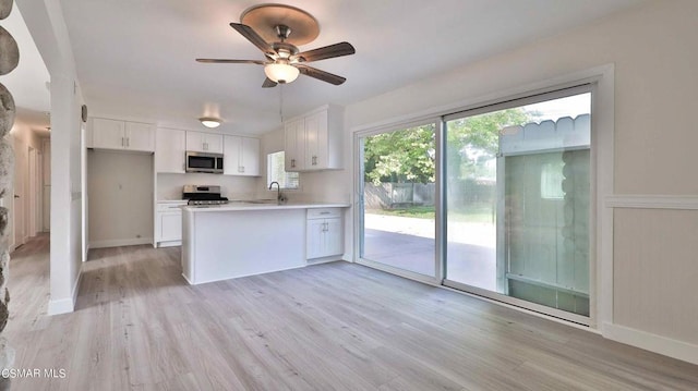 kitchen with sink, ceiling fan, white cabinetry, stainless steel appliances, and light hardwood / wood-style floors