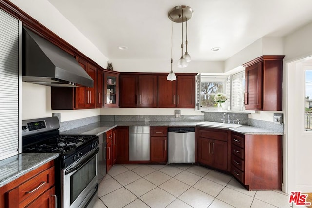 kitchen with light tile patterned flooring, wall chimney exhaust hood, sink, hanging light fixtures, and appliances with stainless steel finishes