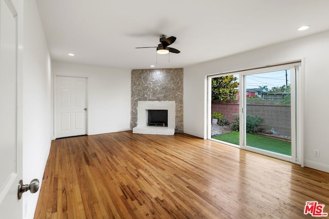 unfurnished living room with a stone fireplace, light hardwood / wood-style floors, and ceiling fan