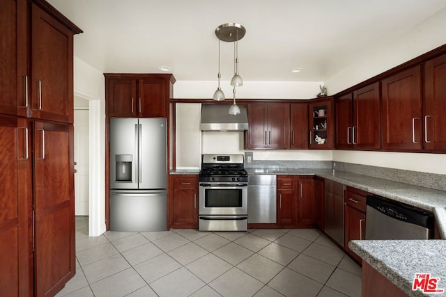 kitchen featuring light tile patterned flooring, wall chimney exhaust hood, decorative light fixtures, dark stone counters, and stainless steel appliances