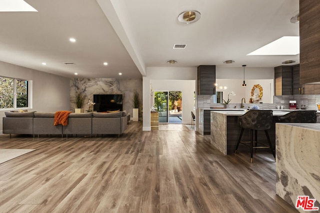 living room with sink, light hardwood / wood-style flooring, and a skylight