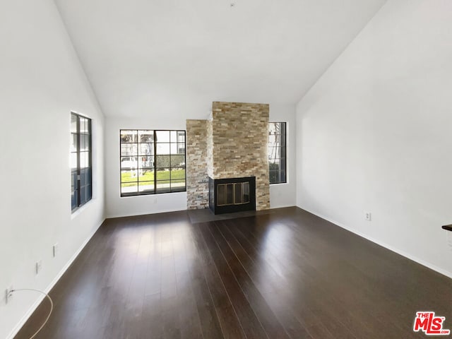 unfurnished living room featuring vaulted ceiling, a stone fireplace, and dark hardwood / wood-style flooring