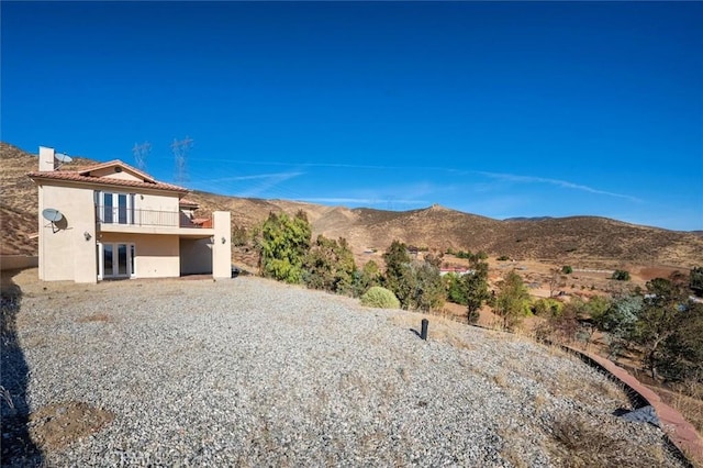view of yard with a mountain view, a balcony, and french doors