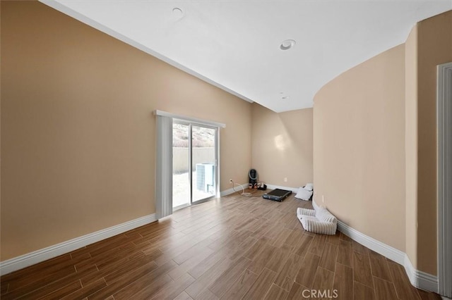 empty room with vaulted ceiling and hardwood / wood-style floors