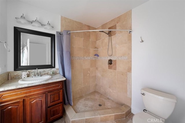 full bathroom with toilet, tiled shower, and vanity