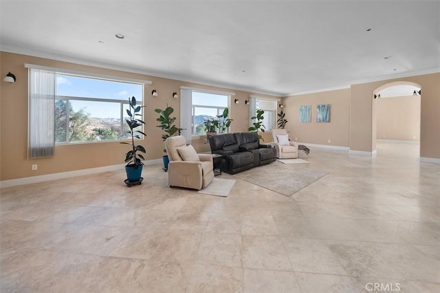 living room featuring ornamental molding, arched walkways, light tile patterned flooring, and baseboards
