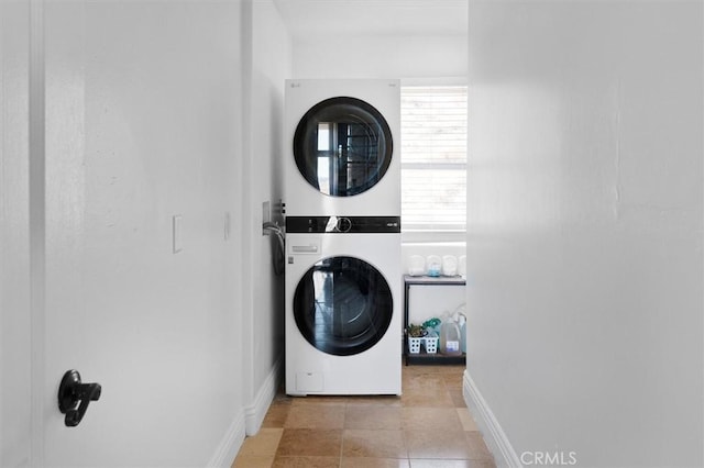 laundry area with stacked washer / dryer and light tile patterned floors