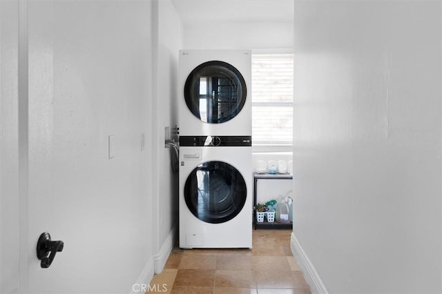 laundry room featuring stacked washer / dryer and baseboards