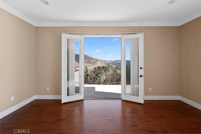 unfurnished room with wood finished floors, a mountain view, and crown molding