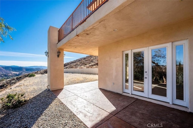 view of patio featuring french doors, a balcony, and a mountain view