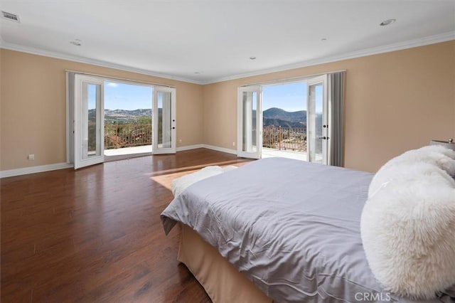 bedroom with multiple windows, a mountain view, dark wood-type flooring, and access to outside