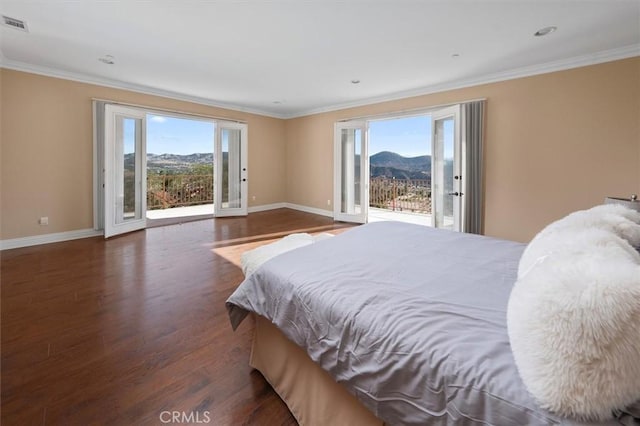 bedroom with a mountain view, wood finished floors, access to exterior, and baseboards