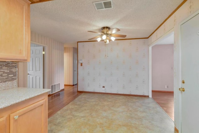 kitchen featuring ceiling fan, light hardwood / wood-style floors, crown molding, light brown cabinets, and a textured ceiling