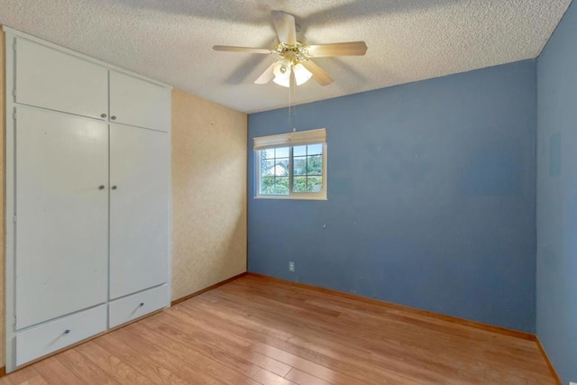 unfurnished bedroom with ceiling fan, a closet, light hardwood / wood-style flooring, and a textured ceiling