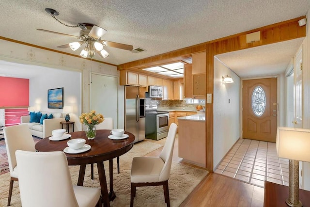 kitchen with stainless steel appliances, decorative backsplash, a textured ceiling, and light hardwood / wood-style flooring