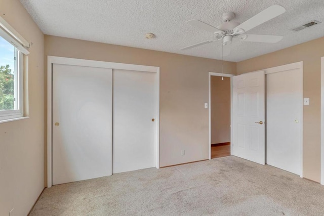 unfurnished bedroom featuring light carpet, a textured ceiling, and ceiling fan