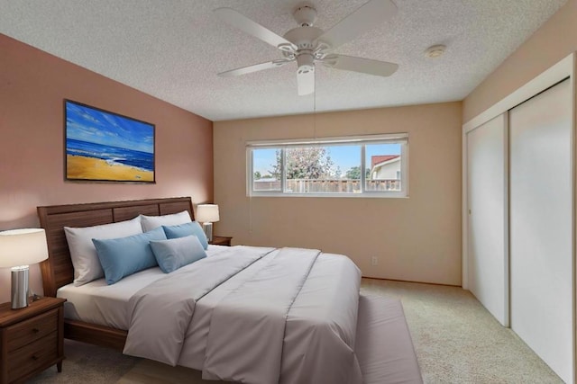 bedroom featuring ceiling fan, light carpet, a closet, and a textured ceiling