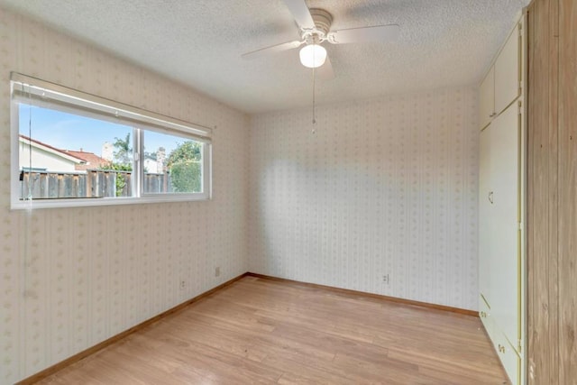 spare room featuring a textured ceiling, light hardwood / wood-style floors, and ceiling fan