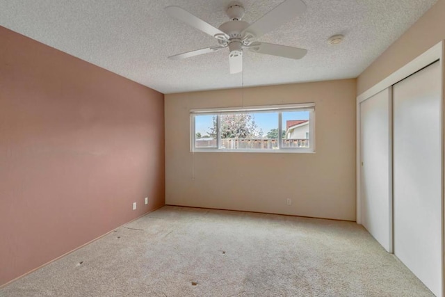 unfurnished bedroom featuring light carpet, a textured ceiling, ceiling fan, and a closet