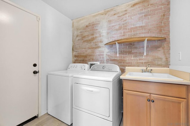 laundry area featuring light hardwood / wood-style flooring, sink, washer and clothes dryer, and cabinets