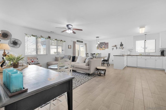 living room featuring plenty of natural light, sink, ceiling fan, and light hardwood / wood-style floors