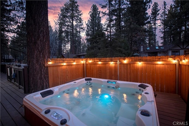 wooden deck with hot tub deck surround and a fenced backyard