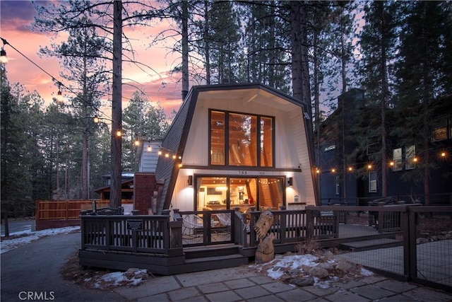 back house at dusk featuring a wooden deck