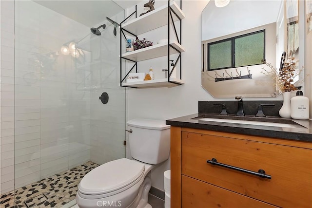 bathroom with tiled shower, vanity, and toilet