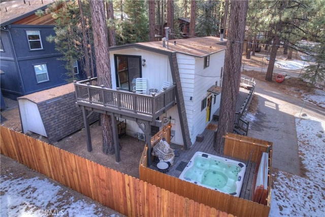 snow covered property with an outdoor hot tub and a wooden deck