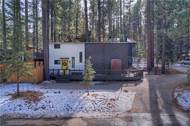 view of front of house featuring a shingled roof and a deck