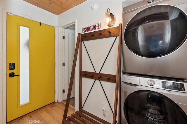 washroom featuring stacked washer and dryer, light wood finished floors, and laundry area