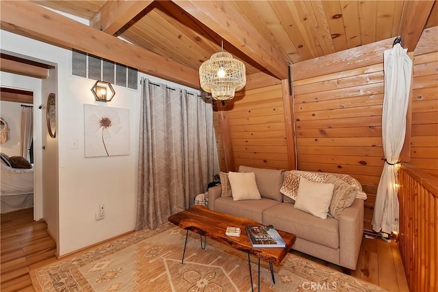 living room with lofted ceiling with beams, light hardwood / wood-style floors, wooden ceiling, a chandelier, and wood walls