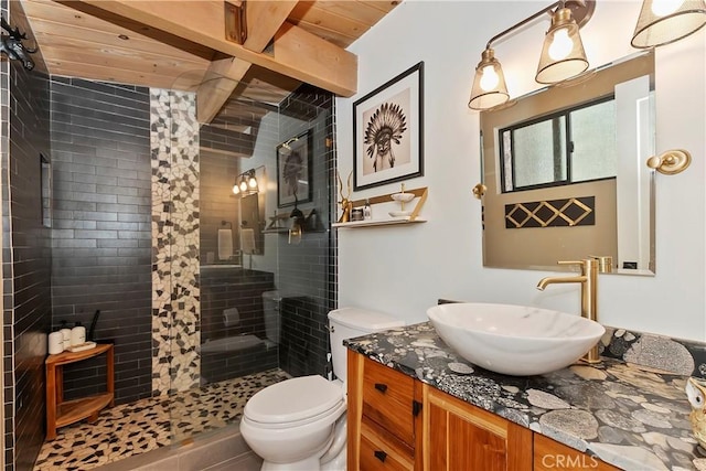 bathroom featuring vanity, tiled shower, wooden ceiling, and toilet