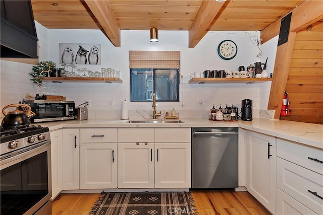 kitchen with appliances with stainless steel finishes, white cabinetry, a sink, and open shelves