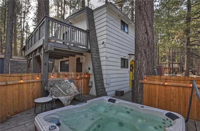 exterior space featuring a deck, fence, and a hot tub