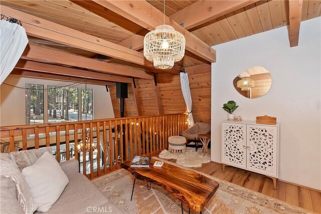 sitting room with light wood-style floors, wood ceiling, wood walls, a chandelier, and beamed ceiling